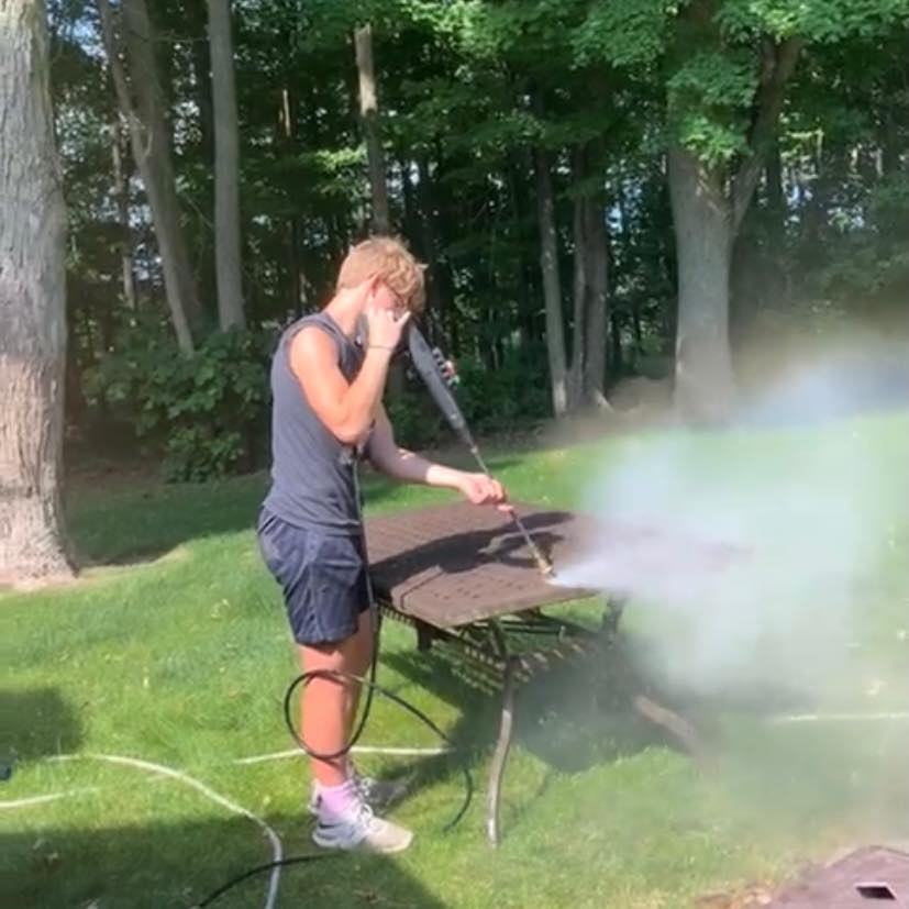 Jamisen Latham, owner of Lawndash Powerwashing, washing a picnic table in Mt. Pleasant Michigan